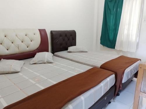 two beds sitting next to each other in a room at Penginapan Syariah in Parit