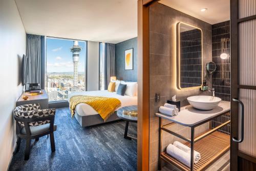 a hotel room with a bathroom with a bed and a sink at voco Auckland City Centre by IHG in Auckland