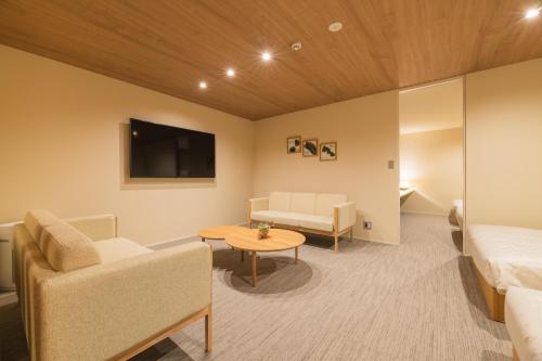 a room with a bed and a couch and a table at HOTEL All Stay Hakata Kukodori in Fukuoka