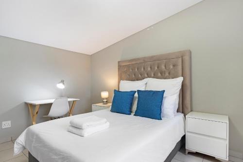a bedroom with a large white bed with blue pillows at The Bolton in Rosebank in Johannesburg