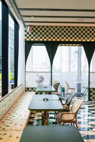 a restaurant with tables and chairs and windows at The Standard, Bangkok Mahanakhon in Bangkok