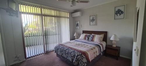 a bedroom with a bed and a large window at Fathoms 2 in Mollymook