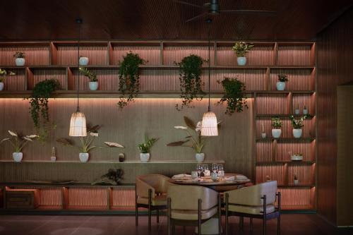 a dining room with a table and chairs and plants at Patina Maldives, Fari Islands in North Male Atoll