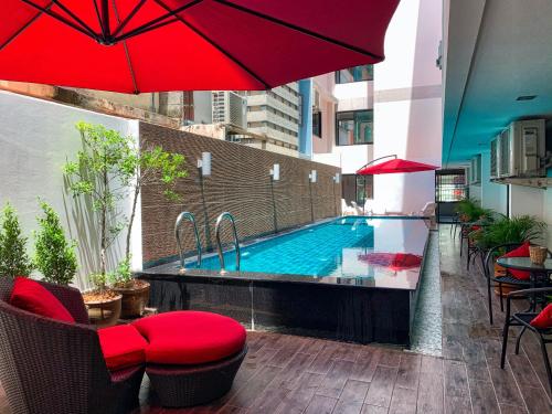 a swimming pool with a red umbrella on a balcony at Jomtien Beach Hostel in Jomtien Beach