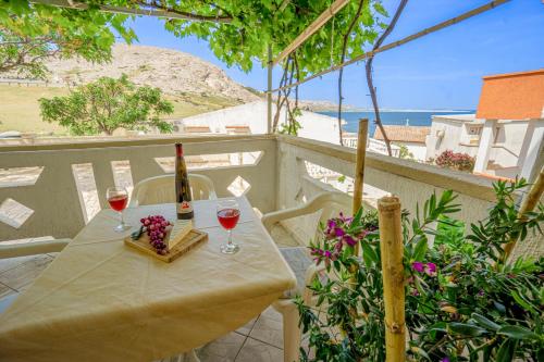 a table with two glasses of wine and a view of the beach at Asta view over sea reed landscape and bay in Metajna