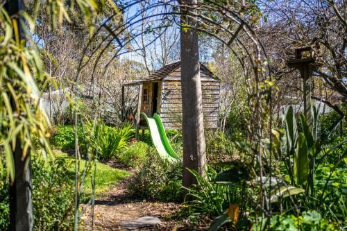 a garden with a house and a green slide at Secret Garden - Luxury Cottage - Giant 85inch TV in McLaren Vale