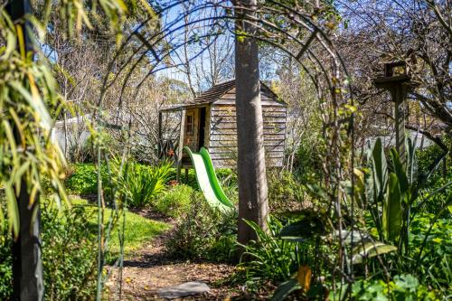 a garden with a house and a green slide at Secret Garden - Luxury Cottage - Giant 85inch TV in McLaren Vale