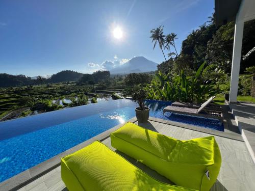 a pool with yellow chairs and a view of the mountains at Villa di Bias in Tirtagangga