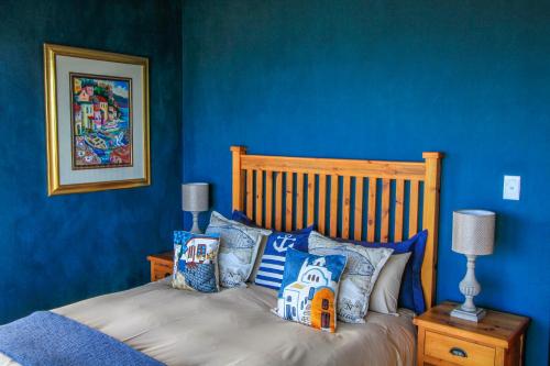 a bedroom with blue walls and a bed with pillows at Two Sunsets B&B in Outeniqua Strand