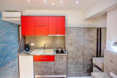 a kitchen with red cabinets and a sink at RENT HOUSE ANEMOS in Iraklitsa