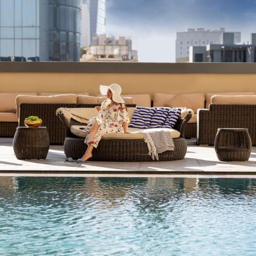 a woman sitting on a couch next to a swimming pool at Ibis Jeddah Malik Road in Jeddah