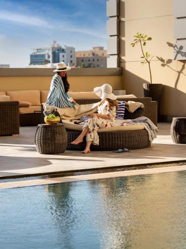 a woman and two children sitting next to a swimming pool at Ibis Jeddah Malik Road in Jeddah