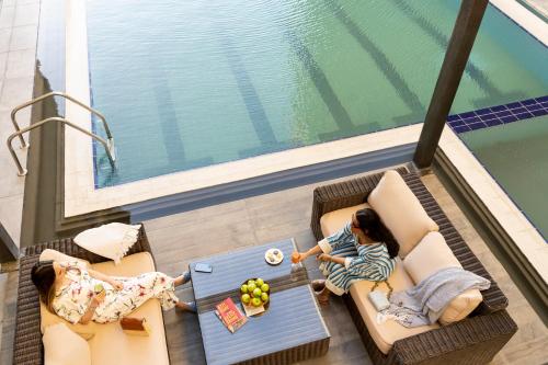 two children sitting on chairs and a table in front of a pool at Ibis Jeddah Malik Road in Jeddah