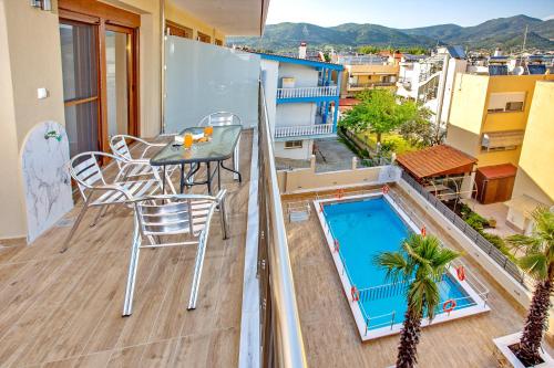 a balcony with a table and chairs and a swimming pool at RENT HOUSE ANEMOS in Iraklitsa
