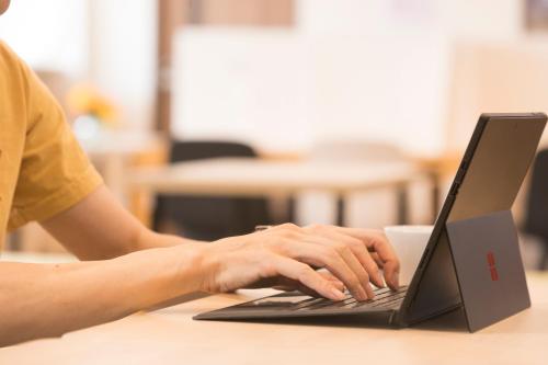 a person typing on a laptop computer on a desk at Wild Cherry Blossom-HOSTEL,TOKYO KOGANEI- in Koganei