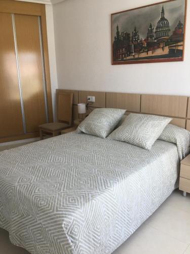 - une chambre avec un lit et une photo sur le mur dans l'établissement Apartamento en La Ribera de Cabanes/Marina D´or., à La Estación
