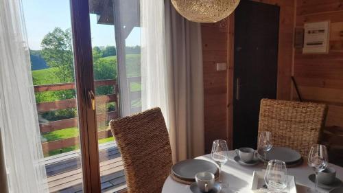 einen Tisch mit einem weißen Tischtuch und Stühlen sowie ein Fenster in der Unterkunft ZACISZE Domek na Kaszubach Brodnica Dolna z balią z jacuzzi in Brodnica Dolna
