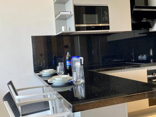 a kitchen with a black counter with plates and glasses at Via Mar Residence - Alanya Experience in Alanya