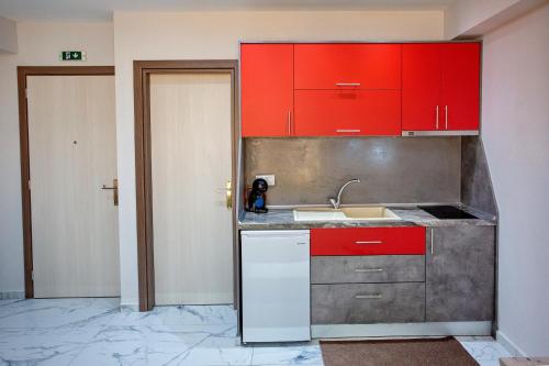 a kitchen with red cabinets and a sink at RENT HOUSE ANEMOS in Iraklitsa