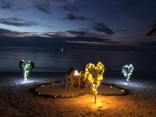 a couple sitting at a table on the beach at night at Sunrise by white sand dhigurah in Dhigurah