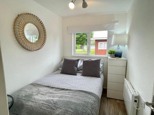 um pequeno quarto com uma cama e um espelho em 197 Broadside Holiday Chalet near Broads & Beaches em Stalham