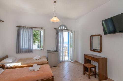 sypialnia z 2 łóżkami, lustrem i telewizorem w obiekcie Esperides w mieście Tinos