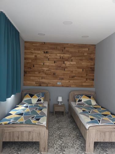 a bedroom with two beds and a wooden headboard at Podlovics Tanya Panzió in Kemecse