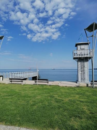 un faro en una playa con dos bancos y el océano en Apartma Olivieri en Koper