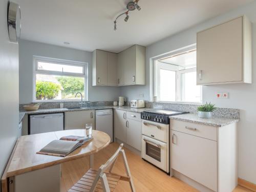 a kitchen with white cabinets and a wooden table at ‘Sea Glimpse’ in the coastal Devon village of East Prawle in West Prawle