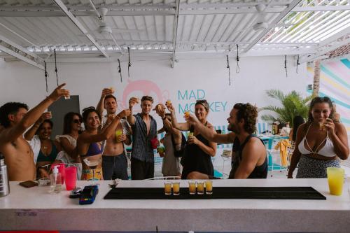 a group of people standing around a table with their hands in the air at Mad Monkey Kuta Lombok in Kuta Lombok