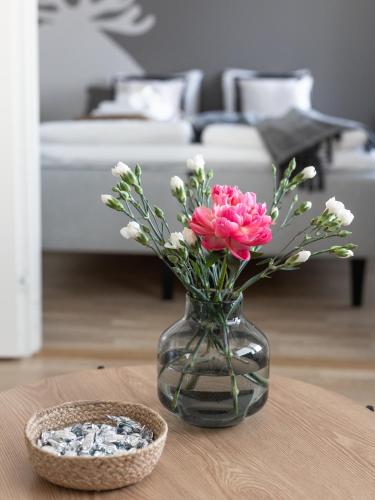 a glass vase with pink flowers on a table at Arctic Railway City Suite in Rovaniemi
