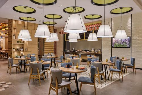 a restaurant with tables and chairs and chandeliers at Swissôtel Clark Philippines in Clark