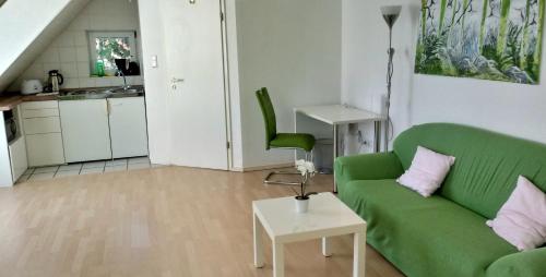 un salon avec un canapé vert et une cuisine dans l'établissement Pension Bunz, à Kelsterbach