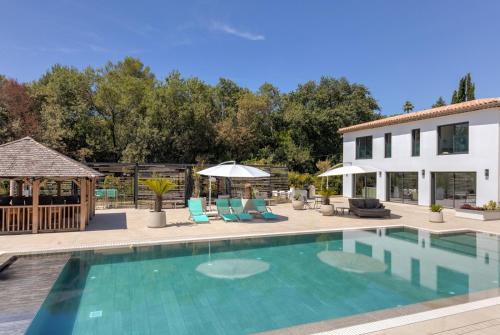 a pool with chairs and umbrellas next to a building at Luxury Zen in Châteauneuf