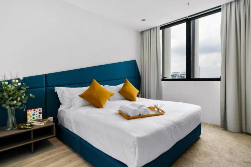 um quarto com uma cama azul e branca com almofadas amarelas em Lumi Tropicana em Petaling Jaya