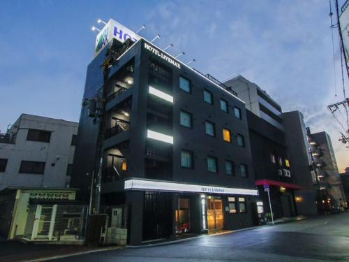 a black building with a sign on top of it at HOTEL LiVEMAX Osaka Umeda Nakatsu in Osaka