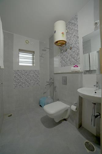 a white bathroom with a toilet and a sink at SM Royal Suites - Hotel near Kempegowda international Airport Bangalore in Devanahalli-Bangalore