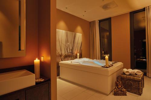 a bathroom with a tub and a sink with two candles at HYPERION Hotel Hamburg in Hamburg