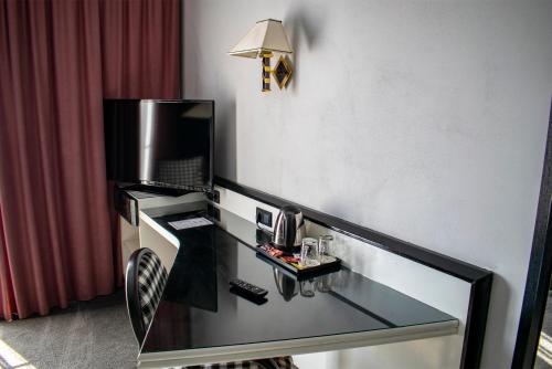 a hotel room with a glass desk with a television at La Conacul Vesel Săpânța in Săpînţa