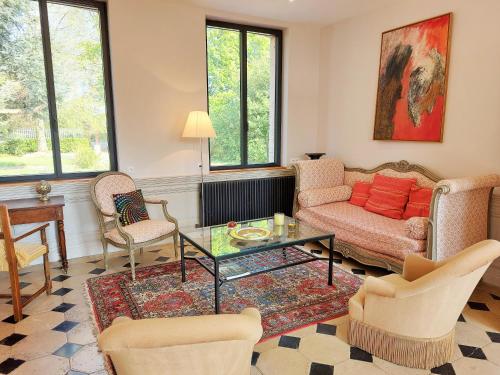 a living room with a couch and chairs and a table at LES JACQUEMARTS NORMANDS Maison d'hôtes - Guesthouse in Belmesnil