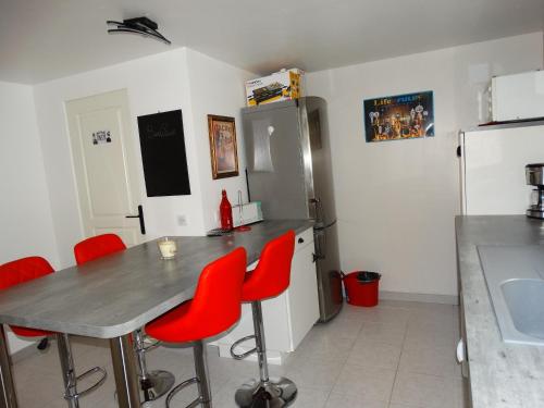 a kitchen with a table with red chairs and a refrigerator at Appartement au calme proche d'un petit bois dans quimper in Quimper