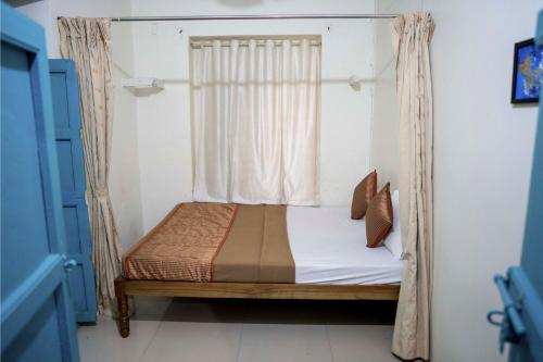 a small bed in a room with a window at The Cottage - by Chandralok Homestays in Kolhapur