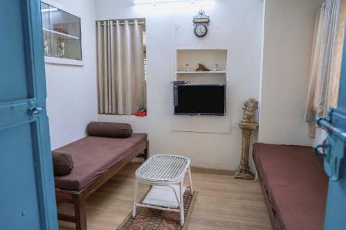 a small living room with a couch and a tv at The Cottage - by Chandralok Homestays in Kolhapur