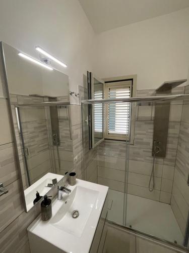 uma casa de banho branca com um lavatório e um chuveiro em Stella Marina em La Caletta