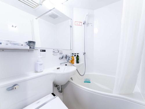 La salle de bains blanche est pourvue d'un lavabo et d'un miroir. dans l'établissement APA Hotel Beppu Ekimae, à Beppu