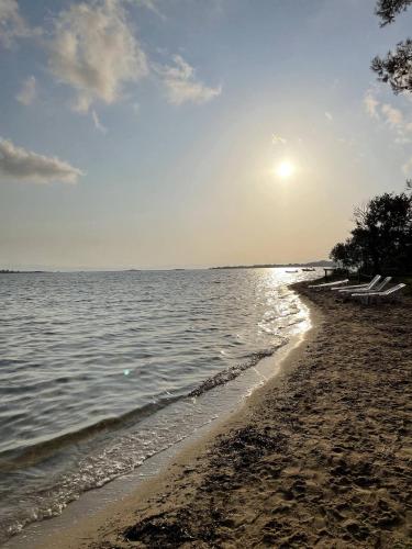 a beach with the sun rising over the water at Makis Nest Apart-Hotel in Vourvourou