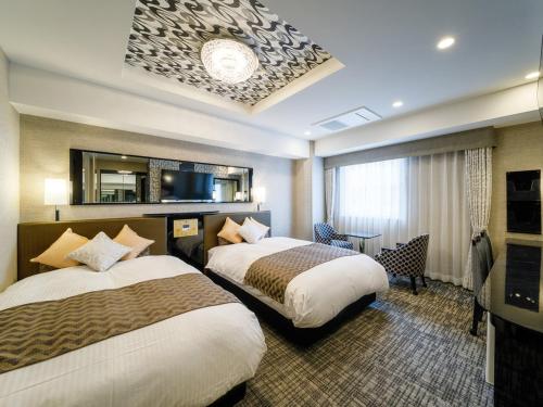 Habitación de hotel con 2 camas y TV en APA Hotel Beppu Ekimae en Beppu