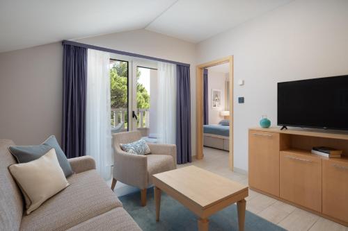 a living room with a couch and a flat screen tv at Aparthotel Flora in Tučepi