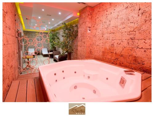 een bad in een kamer met een rode bakstenen muur bij Hotel Dardha in Dardhë