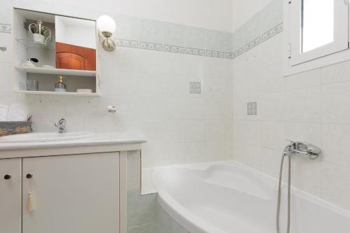 a white bathroom with a tub and a sink at Villa Mythos with Infinity Pool in Dassia